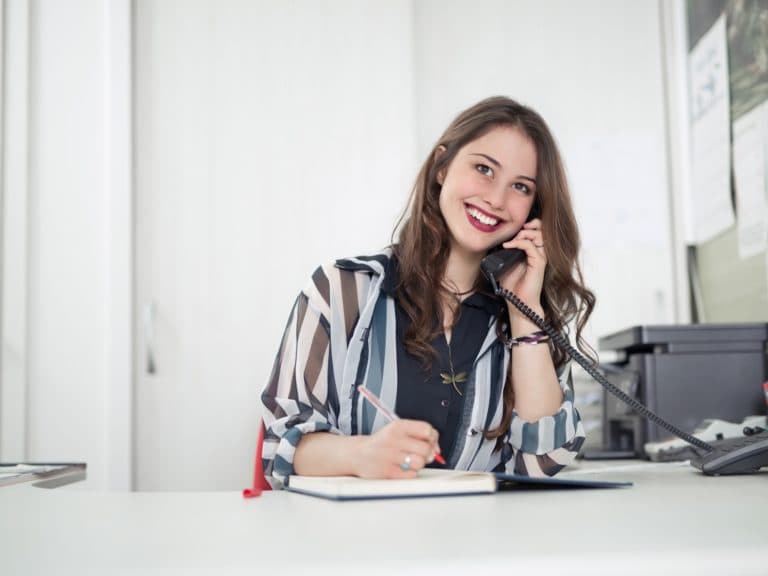 Receptionist on the phone taking notes at a front desk