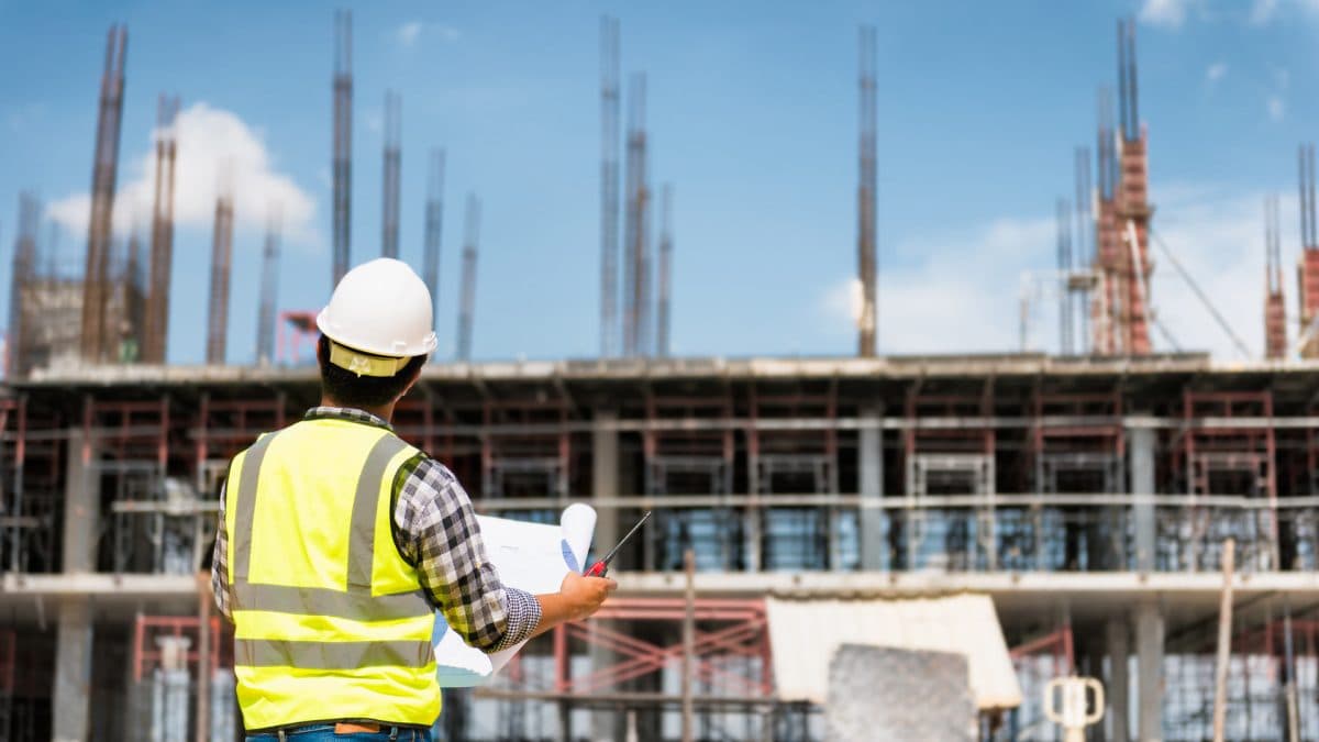 Site engineer reviewing plans in front of a building under construction